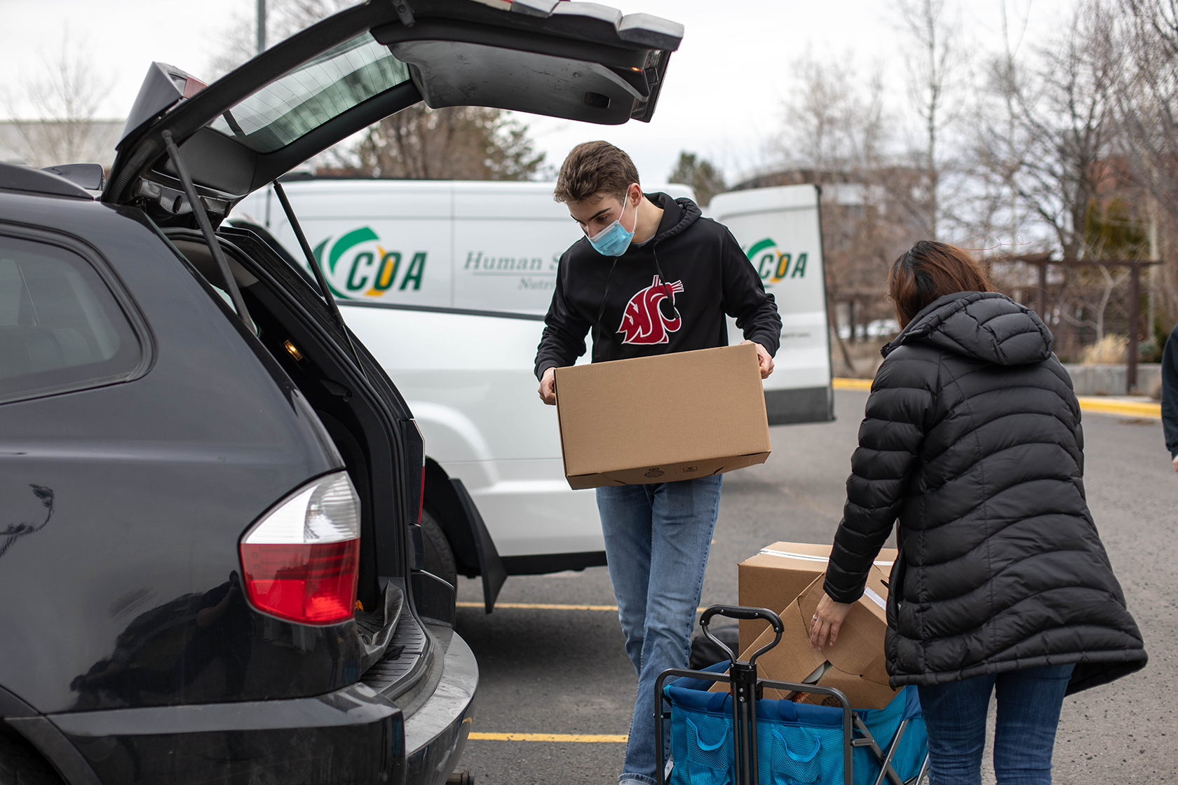 student helping pack items into the back of a car